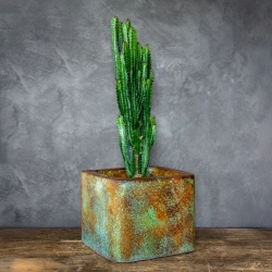 Osłonka na doniczkę z efektem rdzy i zielonej patyny, o gładkiej powierzchni, industrialna i ręcznie wykonana.