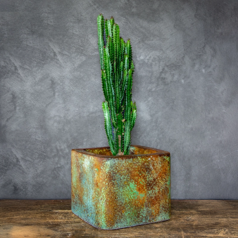 Osłonka na doniczkę z efektem rdzy i zielonej patyny, o gładkiej powierzchni, industrialna i ręcznie wykonana.