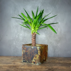 Loftowa osłonka kwadratowa z efektem kortenu i zielonkawą patyną, z abstrakcyjnym motywem twarzy.