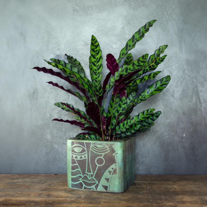 Osłonka na doniczkę z abstrakcyjnym motywem twarzy, w kolorze postarzanego metalu z zielono-turkusową patyną, ręcznie wykonana.