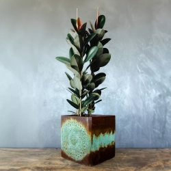 Ręcznie wykonana osłonka z symbolem OM w reliefie, efekt kortenu z turkusową patyną, dekoracja premium.